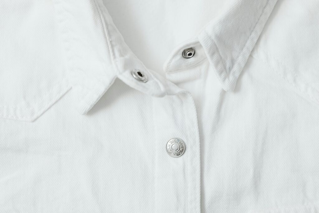 Detailed view of a white shirt with metal buttons and textured fabric.